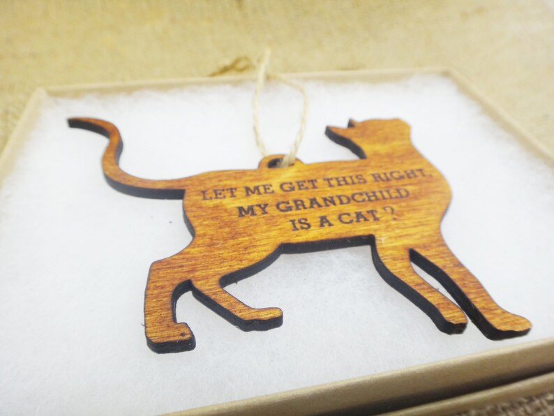 May include: Wooden cat ornament with the text "Let me get this right, my grandchild is a cat?"