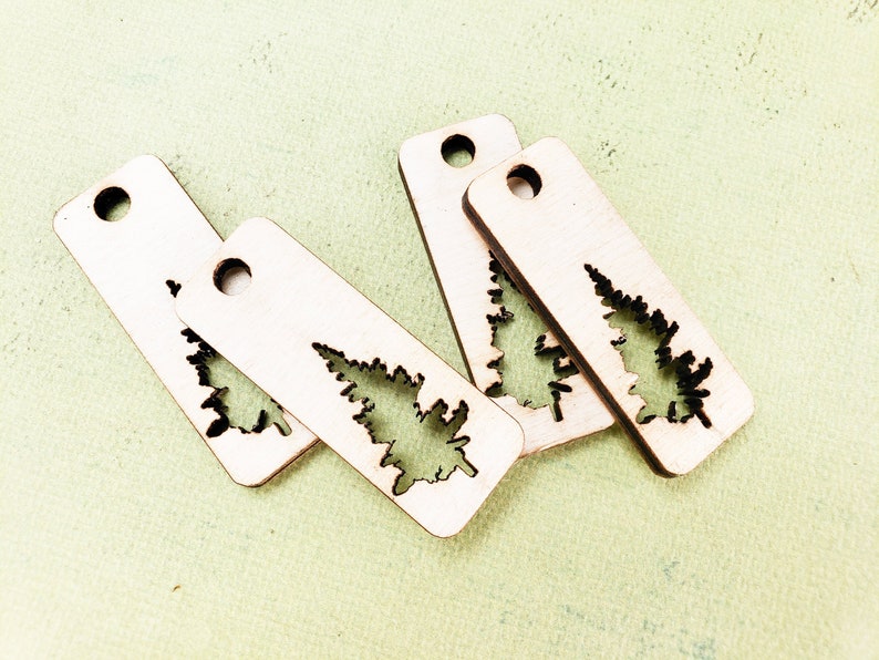 May include: Four unfinished wooden tags with a cutout of a fir tree. The tags have a hole at the top for hanging.