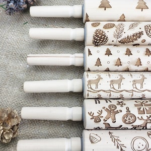 May include: Set of six wooden rolling pins with various Christmas-themed designs, including reindeer, pine trees, snowflakes, and ornaments. The rolling pins are all natural wood and have a light brown color.