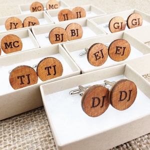 May include: A set of wooden cufflinks in small boxes. Each cufflink is engraved with two initials. The initials include MC, TJ, DJ, EJ, BJ, GJ, JJ, and JY.