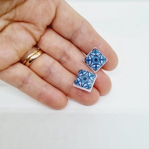 K&ouml;nnte beinhalten: Ein Paar quadratische Ohrringe mit einem blauen und wei&szlig;en Fliesenmuster.