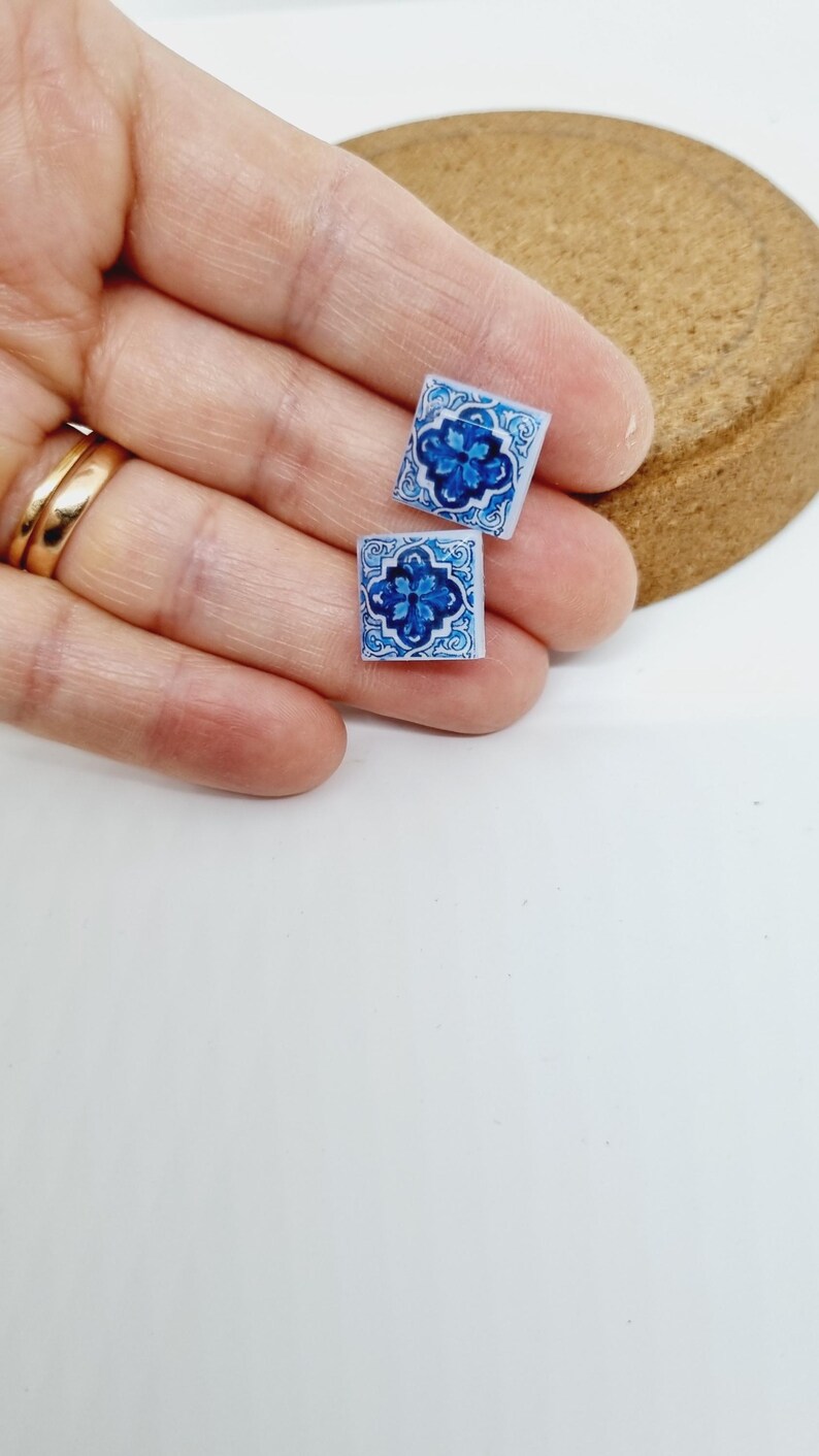 K&ouml;nnte beinhalten: Ein Paar blaue und wei&szlig;e Keramikfliesen-Ohrringe. Die Fliesen haben ein blaues und wei&szlig;es Blumenmuster.