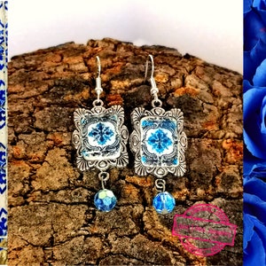 May include: A pair of silver earrings with blue and white patterned tiles, each tile has a silver frame and a blue crystal dangle.