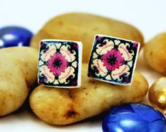 Könnte beinhalten: Ein Paar quadratische Ohrringe mit einem rosa-weißen Blumendesign auf weißem Hintergrund. Die Ohrringe haben einen schwarzen Rand.