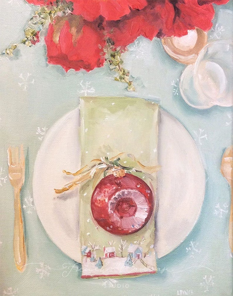Peut inclure: Une mise en place de No&euml;l festive avec une assiette blanche, une fourchette dor&eacute;e et une serviette verte orn&eacute;e d'une boule rouge. La serviette est nou&eacute;e avec un ruban dor&eacute; et pr&eacute;sente une sc&egrave;ne de village d'hiver. Des poinsettias rouges et une tasse en verre sont en arri&egrave;re-plan.