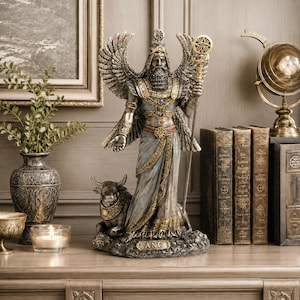 May include: A detailed statue of Anu, a Mesopotamian deity, with outstretched wings and a staff. The figure is adorned in gold and blue, standing next to a bull statue. The base of the statue has the name "ANU" inscribed.