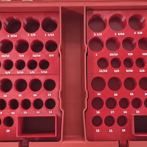 Puede incluir: Una bandeja organizadora de herramientas de plástico rojo con dos secciones simétricas con múltiples recortes circulares para vasos. Cada recorte está etiquetado con texto blanco que indica tamaños imperiales de 7/16 a 1 1/4 pulgadas y métricos de 10 a 24 mm.
