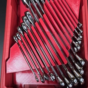 May include: A red toolbox with a clear lid, filled with a set of shiny, silver wrenches. The wrenches are neatly organized in red holders. The toolbox is on a black surface.