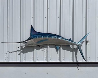May include: A blue and silver marlin fish mount with a long bill, mounted on a white wall.