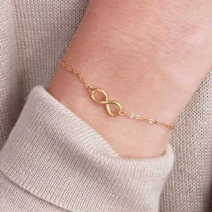 May include: A gold infinity symbol charm bracelet on a delicate chain.