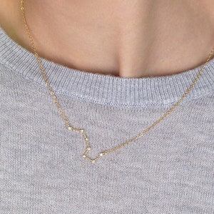 May include: A gold chain necklace with a constellation pendant. The necklace is 17 inches long.