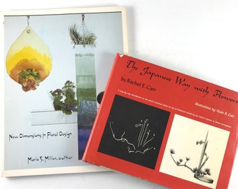 May include: Two books about floral design. The book on the bottom is red with black text and illustrations. The title is "The Japanese Way with Flowers" by Rachel E. Carr. The book on top is white with a photo of a floral arrangement. The title is "New Dimensions in Floral Design" by Marie S. Miller.
