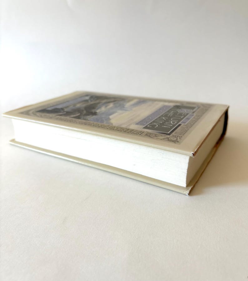 May include: A hardcover book with a cream-colored cover and pages. The book's cover features a detailed illustration with blue and gray tones, and the title "RETURN THE KING" is visible. The book is lying flat on a white surface.