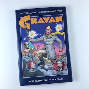 May include: A blue book cover with the title "CRAVAN" in white letters. The book is about a mystery man of the twentieth century. The cover features a man in a gray coat with a yellow scarf, standing on a rocky landscape. The book is by Mike Richardson and Rick Geary.
