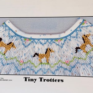 May include: A white and light blue smocked garment with a pattern of tiny horses. The garment has a scalloped neckline with blue and green embroidery. The text "Tiny Trotters" is displayed below the garment.