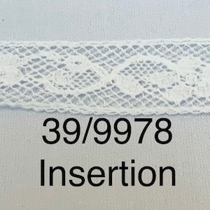 May include: A close-up of a white lace insertion trim with a delicate floral pattern. The trim is displayed against a light blue background. The text "39/9978 Insertion" is printed below the trim.