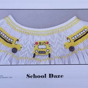 May include: White smocked garment with yellow school bus embroidery. The design features three yellow school buses with black wheels and windows. The garment has a scalloped neckline and the text "School Daze" is visible.
