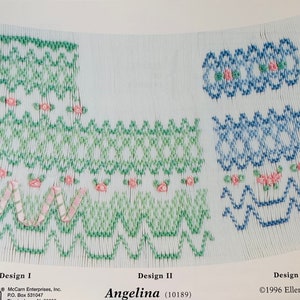 May include: A white paper with three smocking designs in green and blue, with pink floral accents. The designs are labeled I, II, and III, with the name "Angelina" and the McCarn Enterprises logo at the bottom.