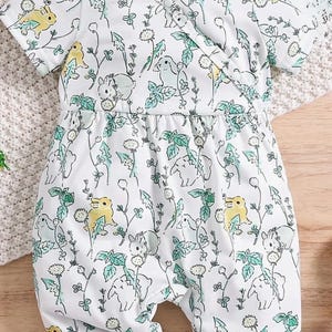 May include: White baby romper with a wrap-style front and short sleeves. The romper is covered in a pattern of yellow birds, gray bunnies, and green foliage. The fabric is soft and lightweight, perfect for warm weather.
