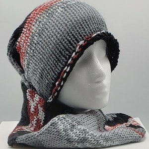 May include: A gray, black, and red knitted hat and scarf set. The hat has a fold-over brim and the scarf is long and wide.