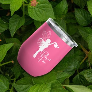 May include: A pink insulated tumbler with a silver lid. The tumbler features a white illustration of a fairy with the text "Plant Pixie". The tumbler is surrounded by green leaves.