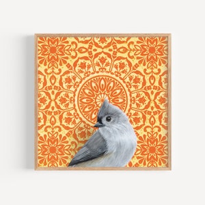 May include: A framed print of a gray tufted titmouse bird perched on a yellow and orange mandala pattern background.
