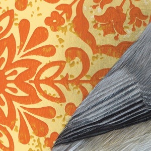 May include: A close-up of a patterned wallpaper with orange and yellow floral designs. The wallpaper is partially covered by a piece of gray textured material.