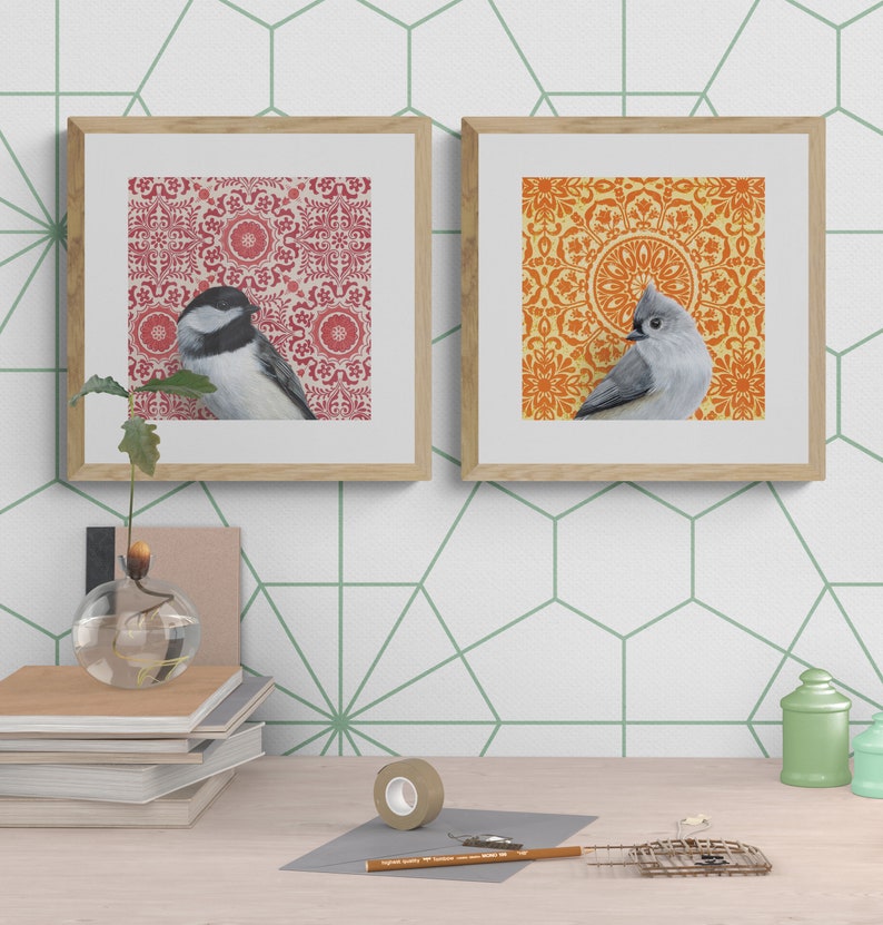 May include: Two framed prints with a bird on each. The print on the left has a red and white patterned background with a black-headed chickadee. The print on the right has an orange and yellow patterned background with a tufted titmouse.