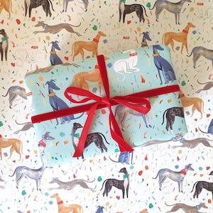 May include: Blue and white gift wrap featuring a repeating pattern of greyhounds in various poses. The greyhounds are illustrated in a whimsical style with colourful accents. The wrapping paper is tied with a red velvet ribbon.