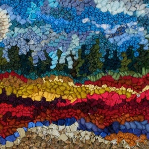 May include: A colorful rug with a landscape design. The rug features a blue sky with a white moon, a green forest, and a red, orange, and yellow field.