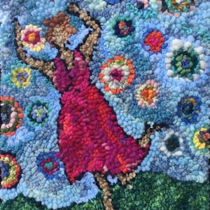 May include: A colorful rug with a woman in a red dress jumping in the air. The rug is made of yarn and has a blue background with colorful flowers.