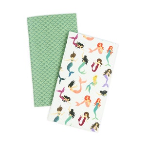May include: Two notebooks with mermaid designs. One notebook has a green scale pattern and the other has a white background with colorful mermaids.