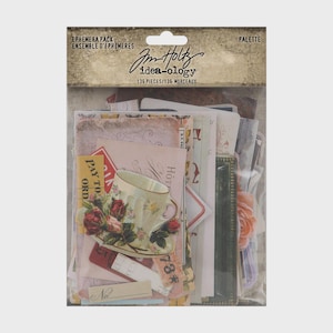 May include: A Tim Holtz idea-ology Ephemera Pack Palette containing 136 pieces of assorted paper cutouts. The clear plastic packaging displays various vintage-style printed cards, including a teacup with roses, tickets, and labels.
