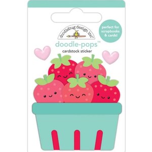 May include: Cardstock sticker featuring a basket of cartoon strawberries with smiling faces. The strawberries are red with green tops, and the basket is light blue with red accents. Two pink hearts are also included in the design. The text "doodle-pops" is visible.