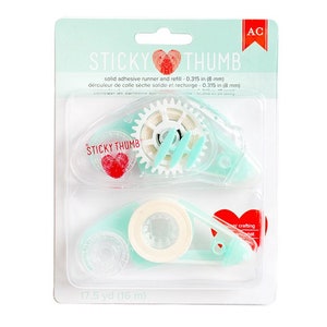 May include: A package of two turquoise blue tape dispensers with a white tape roll. The dispensers are labeled "Sticky Thumb" and have a red heart logo. The package also includes the text "solid adhesive runner and refill - 0.315 in (8 mm)" and "17.5 yd (16 m)".