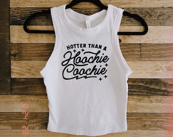 May include: White sleeveless crop top with the text "Hotter than a Hoochie Coochie" in black script with stars and a lightning bolt.