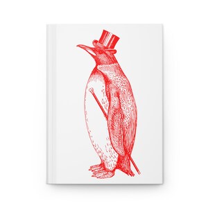 Peut inclure: Un carnet blanc avec une illustration rouge d'un pingouin portant un chapeau haut de forme et tenant une canne. Le pingouin est représenté dans un style vintage détaillé, avec de l'encre rouge sur un fond blanc. Le carnet est rectangulaire et semble être à couverture rigide.