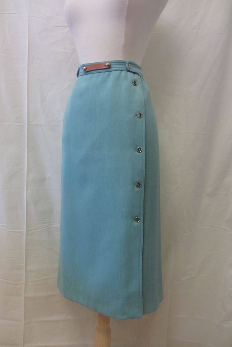 May include: A light blue skirt with a brown leather belt and silver button accents.