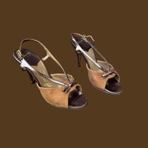 K&ouml;nnte beinhalten: Ein Paar braune und silberne High-Heel-Schuhe mit Peeptoe-Design und Schleifendetail. Die Schuhe sind aus Leder und haben einen Slingback-Riemen.