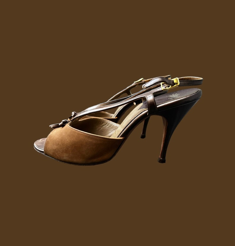 K&ouml;nnte beinhalten: Braune Wildledersandalen mit goldener Schnalle und einem Riemen &uuml;ber dem Fu&szlig;.