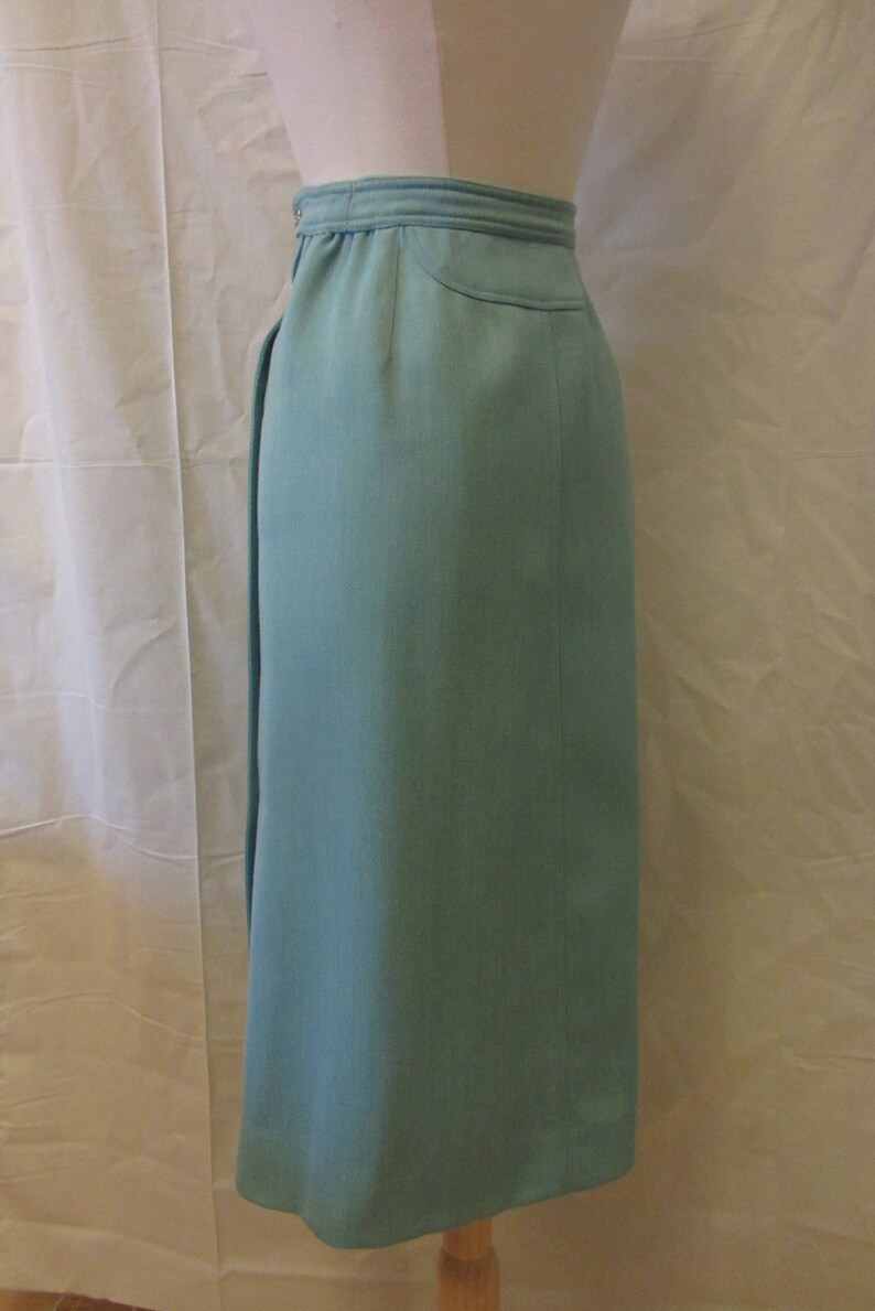 May include: A light blue skirt with a high waist and a straight cut. The skirt is made of a smooth fabric and has a simple design.