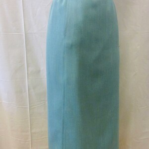 May include: A light blue skirt with a brown leather belt and a silver button. The skirt is knee-length and has a straight silhouette.
