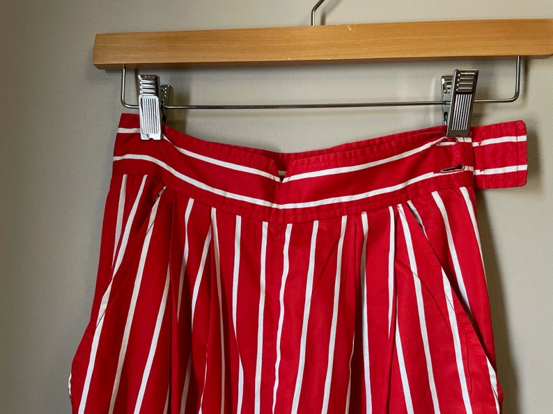 May include: Red and white striped high-waisted shorts with a wide waistband and pleats.