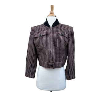 May include: A cropped black and pink houndstooth patterned jacket with a zipper closure and a black collar.