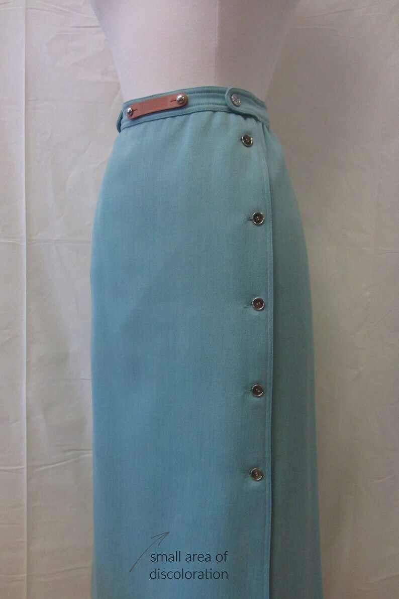May include: A light blue skirt with a brown leather belt and silver buttons. There is a small area of discoloration on the skirt.