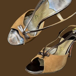 K&ouml;nnte beinhalten: Ein Paar braune Wildledersandalen mit Absatz, Peeptoe und Schleife. Die Sandalen haben eine goldene Schnalle und sind mit "A'mano Hand Made" und "Barry Stuart" beschriftet.