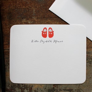 May include: A white card with rounded corners features a pair of red baby shoes and the text "Willie Elizabeth Monier".