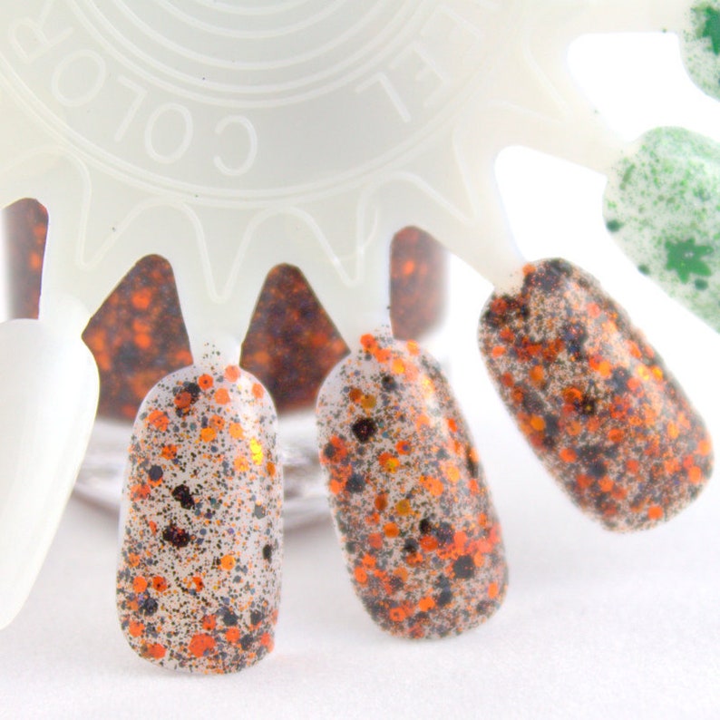 May include: A close-up of a nail polish color chart with four different shades of orange, black, and gold glitter nail polish.