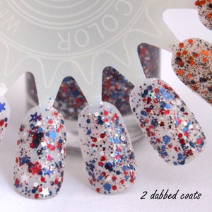 Peut inclure: Un flacon de vernis &agrave; ongles transparent avec des paillettes rouges, blanches et bleues. Les paillettes sont en forme d'&eacute;toiles et de cercles. Le flacon est &eacute;tiquet&eacute; "COLOR SHOW". L'image montre deux couches de vernis appliqu&eacute;es sur un nuancier &agrave; ongles.