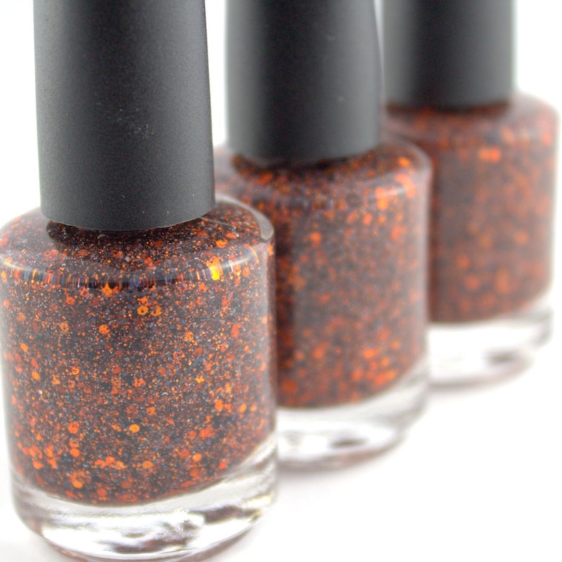 May include: Three bottles of nail polish with black caps and a glittery orange and black polish inside.